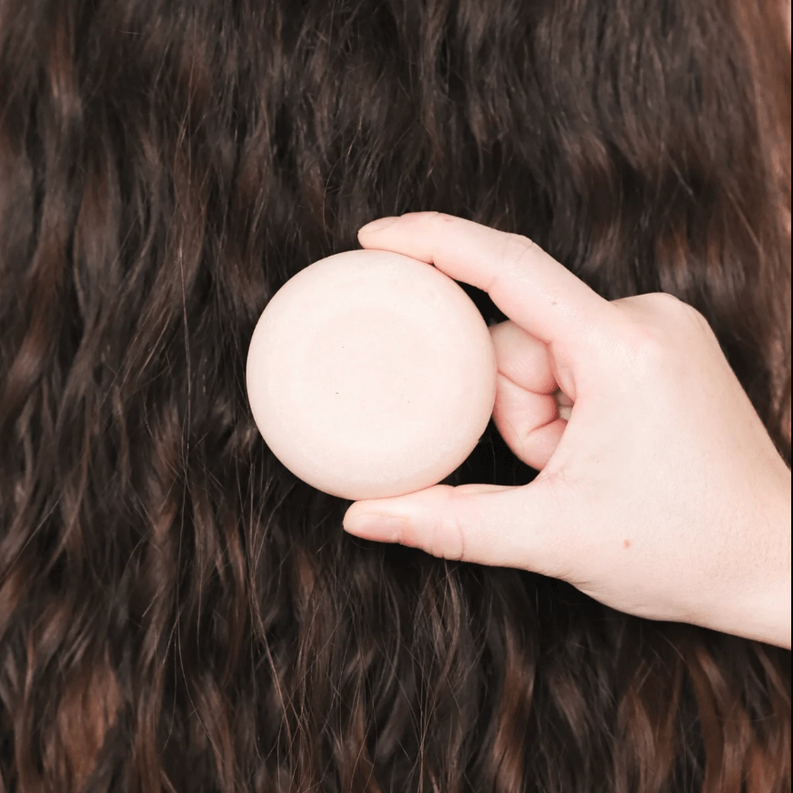 Hand holding a solid shampoo for dry hair, showcasing its nourishing care and natural ingredients for hydrated locks.