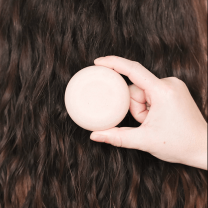 Hand holding a solid shampoo for dry hair, showcasing its nourishing care and natural ingredients for hydrated locks.
