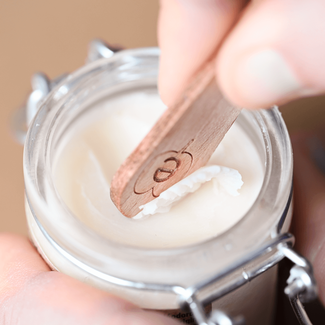 Applying natural solid deodorant with a wooden stick, highlighting aluminium-free and clean beauty features.