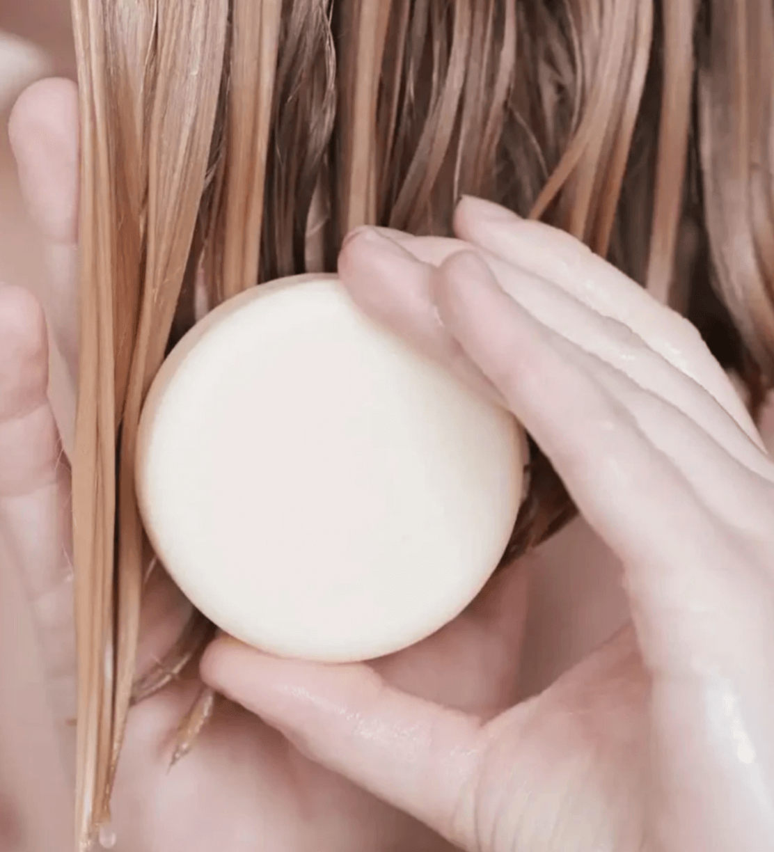 A person applying a solid conditioner for all hair types, showcasing its natural formula and clean beauty values.