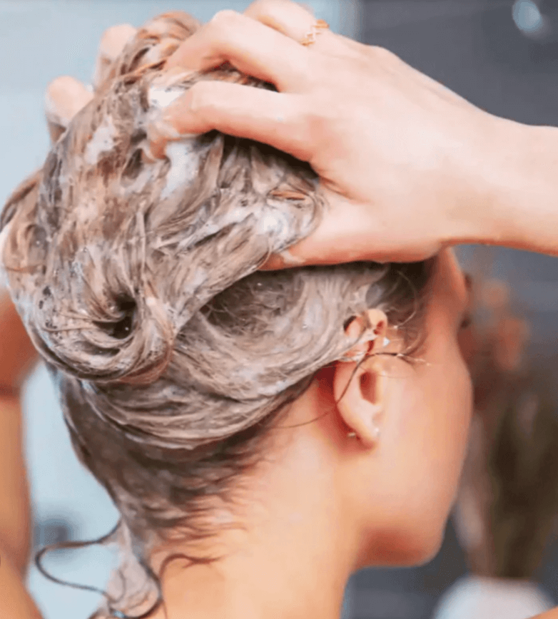Applying natural shampoo for balanced daily hair care in a clean beauty routine.